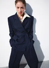 Pantalón de traje tiro medio, corte recto y largo, con diseño de raya diplomática, pinzas y bolsillos laterales.