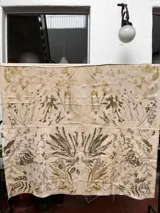 Mantel rectangular de algodón color crudo con estampado botánico en tonos marrones y verdes.