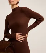 Vestido midi de punto acanalado, color negro, con cuello alto y mangas largas. Presenta un corte ajustado al cuerpo.