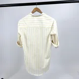 Camisa de algodón a rayas verticales color crema y blanco, con cuello mao y mangas largas con puños abotonados.