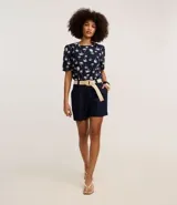 Short recto de cintura alta color crudo, confeccionado en viscolino, con trabillas en la cintura, pliegues y cierre tradicional. Incluye cinturón de rafia artificial con hebillas de argollas.