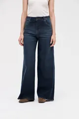 Jean de corte wide leg con tiro medio, confeccionado en denim azul oscuro con lavado uniforme. Presenta diseño de cinco bolsillos, cierre frontal con botón y cremallera, y perneras amplias y holgadas desde la cadera hasta el bajo.