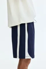 Short de baño azul marino con bandas laterales blancas, cintura elástica con cordón de ajuste blanco y dobladillo curvo.