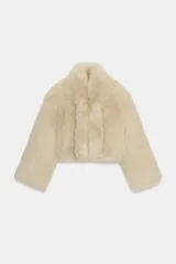 Abrigo corto de piel sintética en color beige, con cuello solapa, manga larga y forro interior.