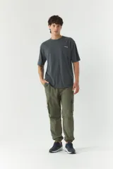 Pantalón cargo verde militar de nylon con cintura ajustable, bolsillos laterales con solapa y puños elásticos.