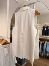 Chaleco sastrero color beige con solapas clásicas, bolsillos con solapa y cierre frontal con un botón.