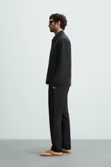 Pantalón negro de corte regular fit, confeccionado en tejido de lino. Presenta cintura con botón y cierre de cremallera, bolsillos frontales y bolsillos traseros de doble vivo.