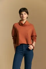 Polera de tejido de punto color naranja con cuello alto de caída relajada y diseño de líneas en relieve. Presenta una silueta holgada con hombros caídos y mangas largas.