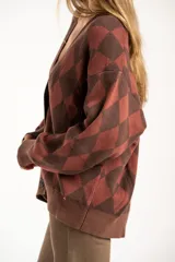 Cardigan de punto con diseño de rombos en tonos marrón y terracota, cuello en V, cierre frontal con botones y mangas largas con puños acanalados.