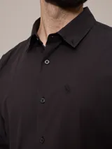 Camisa negra de algodón de manga larga, con cuello clásico y cierre frontal con botones.