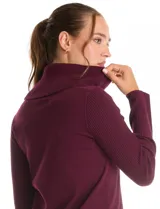 Buzo de punto color bordó con cuello volcado amplio y mangas largas. Presenta una costura central vertical en el frente y diseño con tajos laterales en el ruedo, siendo ligeramente más largo en la parte posterior.