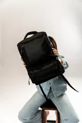 Mochila negra con múltiples bolsillos con cierre y manija superior.