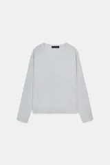 Jersey de punto color gris claro con hilo metalizado, de cuello redondo y manga larga. Bajo recto con aberturas laterales.