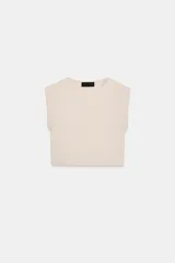 Top corto de punto color beige claro, con cuello redondo y mangas cortas tipo hombrera.
