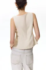 Chaleco sastrero color beige, entallado, con escote cuadrado, tirantes anchos y cierre frontal con botones revestidos.