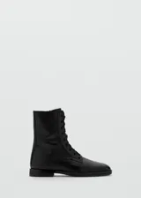 Botas de caña alta negras de estilo militar, con cordones frontales y cierre lateral, confeccionadas en piel vacuna con suela de goma.