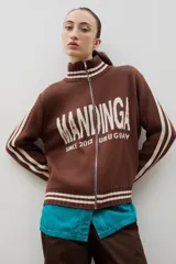 Campera tejida de punto color marrón con cierre frontal completo, cuello alto y detalles de rayas blancas en cuello, puños y ruedo. Presenta el logo de la marca estampado en el frente.