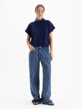 Chaleco de tejido de punto en color celeste, con cuello redondo y mangas cortas con terminación en rib. Presenta un diseño holgado con aberturas laterales en el ruedo y un pequeño bordado decorativo en la parte inferior.