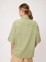 Camisa de manga corta celeste, confeccionada en mezcla de algodón y lino, con cuello camisero y cierre frontal de botones.
