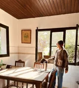 Cardigan de punto color beige con escote en V, cierre frontal con botones, bolsillos delanteros aplicados y detalle de flecos en el ruedo.