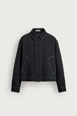 Sobrecamisa de corte regular fit color negro con pespuntes en contraste blancos. Presenta cuello solapa, mangas largas con puños abotonados, bolsillos frontales de vivo y cierre de cremallera oculta por solapa con botones.