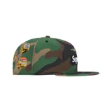 Gorra tipo snapback de Supreme en colaboración con New Era, con estampado de camuflaje y parche rectangular negro con el logo de la marca en blanco en la parte frontal.