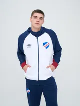 Campera deportiva Umbro del Club Nacional de Football, modelo con capucha, cierre frontal, bolsillos laterales y mangas raglán. Diseño en color blanco con mangas y detalles en azul marino y rojo.