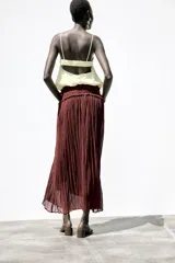 Top corto color crema confeccionado con lino, escote pico y tirantes finos. Detalle de espalda abierta con tira elástica horizontal y bajo abullonado con elástico interior.