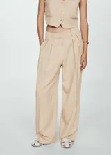 Pantalon de corte wideleg color beige, con tiro medio, detalle de pinzas frontales, trabillas para cinturon y cierre frontal con boton, gancho y cremallera.