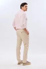Pantalón de lino color beige, de corte recto y cintura elastizada con presillas para cinturón y bolsillos laterales.