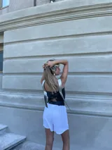 Top corto negro de ecocuero con tirantes finos plateados y espalda descubierta.