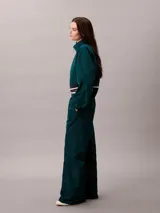 Pantalón deportivo Calvin Klein de pierna ancha y tiro medio, confeccionado en tafetán color verde oscuro. Posee cintura elástica con logo de la marca visible.
