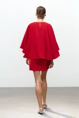 Vestido corto rojo de cuello redondo y manga corta tipo capa. Cierre en la espalda con abertura y botón.