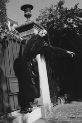 Abrigo largo negro de efecto piel con cuello de pelo sintético desmontable, solapas con muescas, manga larga, bolsillos laterales, forro interior a tono y cierre frontal con botones. Incluye cinturón del mismo material para ajustar a la cintura.