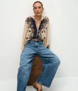Pantalón barrel de jeans de tiro medio, con piernas amplias y afuniladas en el ruedo. Posee bolsillos funcionales, trabillas y cierre delantero con botón y cremallera.