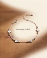 Pulsera de plata 925 con diseño de cadena fina, detalles de cuentas esféricas y un dije central en forma de trébol compuesto por cuatro pequeños corazones, algunos con apliques de circón.