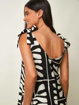 Vestido midi negro con estampado gráfico en blanco, de corte amplio y escote redondo con tirantes anudados en los hombros.