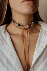 Gargantilla de cuero marrón con doble tira y dijes de flores espejadas.