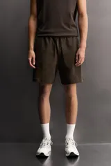 Short jogger marrón de corte relaxed fit, confeccionado en tejido compacto de algodón, con cintura elástica ajustable, bolsillos frontales en la cadera y bolsillo trasero de plastrón.
