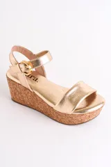Sandalia plateada con plataforma de corcho, diseño cruzado y tira con hebilla al tobillo.