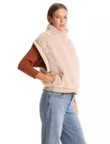 Chaleco de piel sintética en color beige, con cuello alto, cierre frontal metálico y terminaciones en tejido rib en el ruedo y sisas.