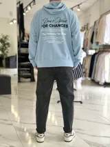 Canguro oversize color beige, con capucha y amplio estampado tipográfico en la espalda.
