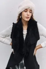 Chaleco negro con interior y bordes de piel sintética, diseño abierto sin cierre.