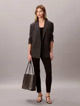 Cartera tote Calvin Klein de diseño estructurado, color negro y marrón con estampado de monograma CK en toda la superficie. Cuenta con asas de mano dobles y finas, y viene acompañada de una mini cartera lisa con cierre y detalle del logo de la marca en dorado.