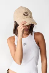 Gorro tipo baseball de tela tipo peluche color crudo, con bordado central en color marrón.