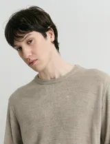 Sweater de tejido de punto con escote redondo y manga larga. Presenta un diseño clásico con detalles de terminación en sisas y cuello.