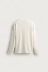Camiseta relaxed fit de manga larga confeccionada en tejido waffle con mezcla de algodón y cáñamo. Presenta cuello redondo con cierre frontal parcial de botones.