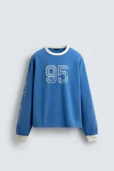 Camiseta de manga larga con cuello redondo y ajuste relajado. Presenta un efecto lavado, acabados en rib en cuello y puños, y un estampado frontal con el número 95 en contraste.