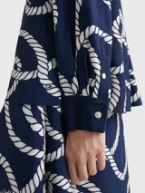 Blusa vaporosa Tommy Hilfiger de color azul marino con estampado integral de cuerdas blancas de estilo marinero. Presenta cuello en V con cordones para anudar, mangas largas con puños abotonados y corte regular.