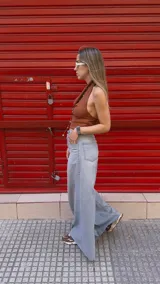 Pantalón de jean celeste de tiro medio con pierna extra ancha y caída fluida, con bolsillos delanteros y traseros, y cierre frontal con cremallera y botón metálico.